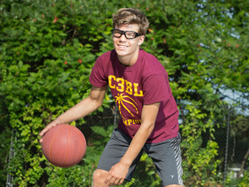 Teenage boy wearing sports goggles while playing basketball